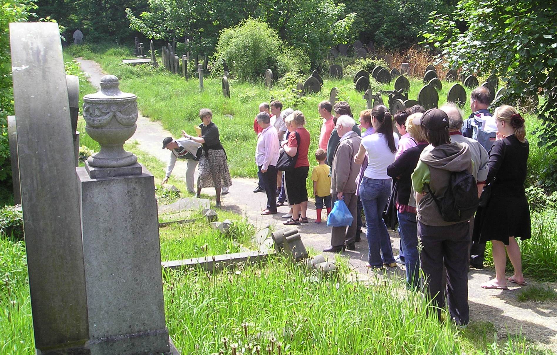 A tour group in a cemetery. Summer sunshine and grey gravestones.